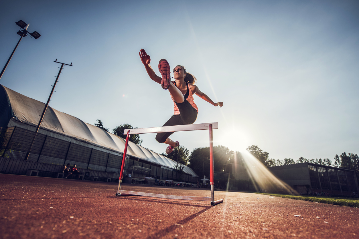 Low angle view of female athlete hurdling on sports race.